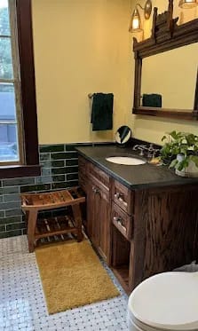 Warm traditional bath, green subway wainscot, dark-stained oak vanity.
