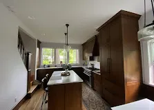 White-oak shaker kitchen with island, white quartz counters, and pendants over a long bank of cabinetry. Representative of Four Squared finish work.