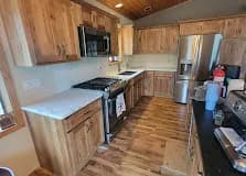Knotty hickory galley kitchen with white quartz and stainless French-door fridge.