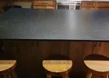 Dark soapstone island, light-wood bar stools.