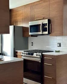 Walnut flat panel: Flat-panel cabinetry in stained walnut. Clean modern, lets the wood grain do the work.