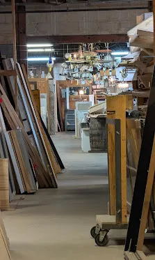 A trim-and-moulding aisle vignette: stacked profiles, warm overhead light. Representative of what you find in the warehouse.